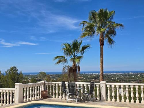 a balcony with two palm trees and a swimming pool at Villa Mariposa in Casas Albardanera
