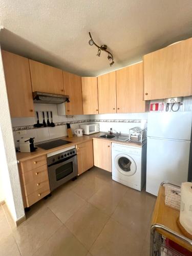 a kitchen with wooden cabinets and a washer and dryer at Bol02 - Modern 2 bedroom apartment in Bolnuevo in Bolnuevo