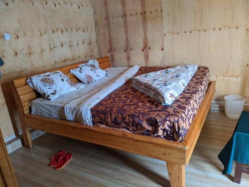 a wooden bed with pillows on it in a room at NYUNGWE VILLAGE in Kitabi