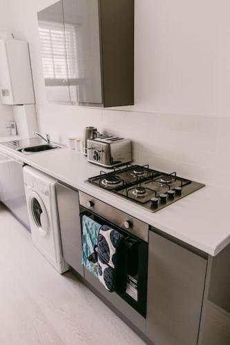 a white kitchen with a stove and a sink at Dream Beach View in Weymouth