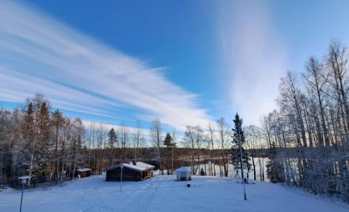 a snow covered field with a building and trees at The Haven of Riverside - Villa Sieripirtti in Rovaniemi