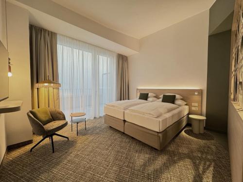 a hotel room with a bed and a chair at ARCOTEL AQ Wien in Vienna
