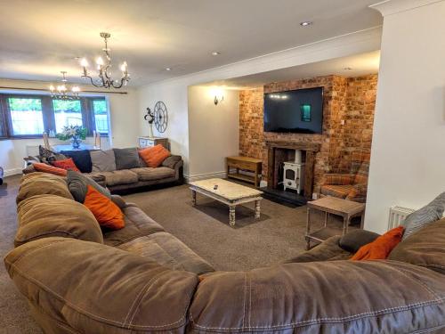 a living room with a large couch and a fireplace at Spacious Home for Large Families and Contractors in Wolverhampton