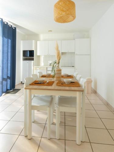 - une cuisine blanche avec une table en bois et des chaises blanches dans l'établissement Maison 2 chambres, à Saint-Hilaire-de-Riez