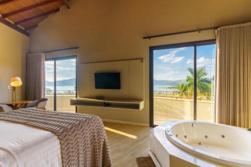 a bedroom with a bed and a tub and a television at Pousada Terramare in Guapé