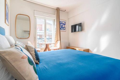 Cette chambre dispose d'un grand lit bleu et d'une fenêtre. dans l'établissement Studio ensoleillé aux portes de Paris Montreuil-II, à Montreuil