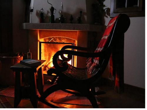 a rocking chair in front of a fireplace at Casa Do Grilo Soajo in Soajo