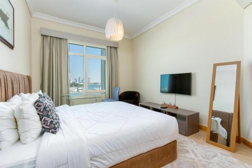 a bedroom with a white bed and a television at Bespoke Residences - 2 Bedroom Apartment Sea View with Beach Access in Dubai