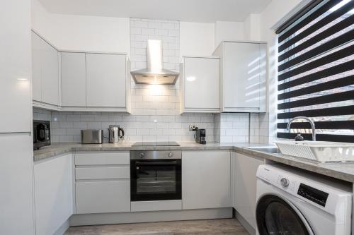 a kitchen with white cabinets and a dishwasher at 2 Ensuite Bed Home Near Shops in Denton