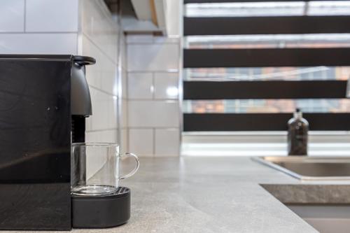 a coffee maker with a glass on a counter at 2 Ensuite Bed Home Near Shops in Denton