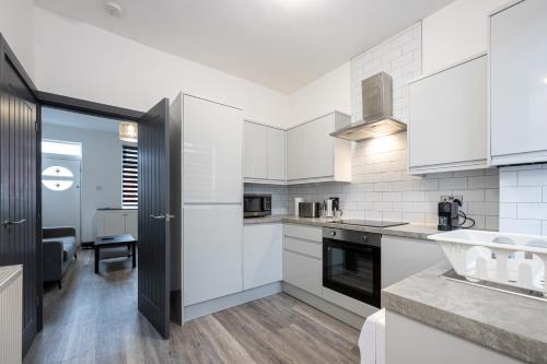 a kitchen with white cabinets and a sink at 2 Ensuite Bed Home Near Shops in Denton