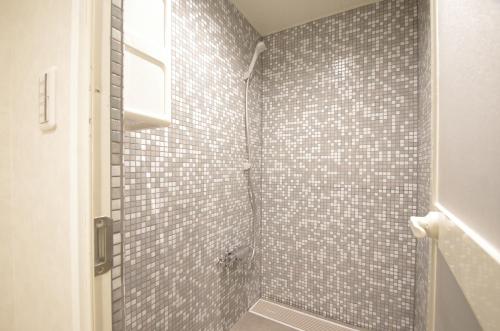 a bathroom with a shower with a tiled wall at Hotel Imalle Haneda in Kawasaki
