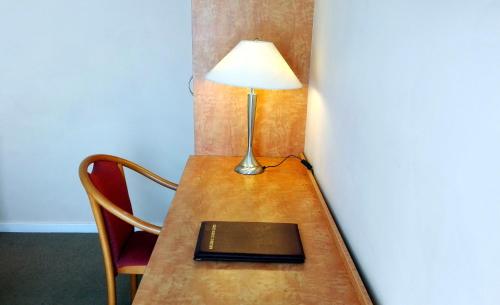 a desk with a lamp and a book on it at Glen Inn in Glen Waverley