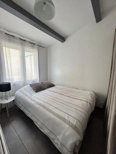 a white bedroom with a bed and a window at Charmante petite maison in Savigny-sur-Orge