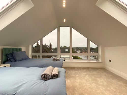 a attic bedroom with two beds and a large window at House - Sleeps 9 & Private Garden in Leeds