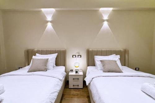 two beds in a room with lights on the wall at The Built-Up 2 BDR Condo 15 min to CAI Airpt in Cairo