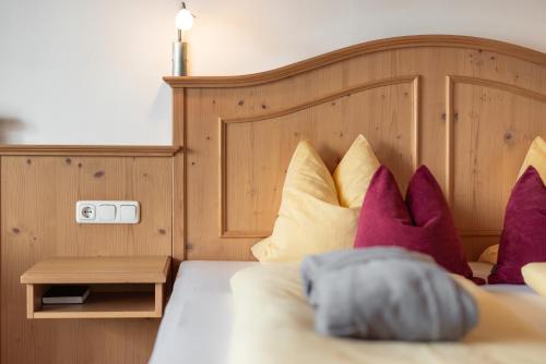 a bedroom with a bed with purple and yellow pillows at Hotel Königsleiten Vital Alpin in Königsleiten