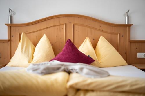 a bed with yellow and purple pillows on it at Hotel Königsleiten Vital Alpin in Königsleiten