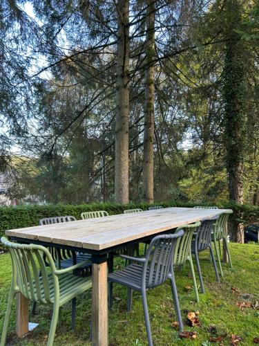 a wooden table with chairs around it in a park at Cacele - La croisette 5 appartementen en 6 tweepersoonskamers in Vresse-sur-Semois
