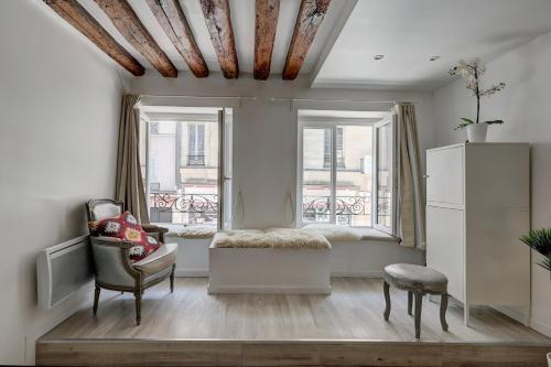 - un salon avec un canapé, une chaise et des fenêtres dans l'établissement Bluestay 112 - Élégant Appartement à Paris, à Paris