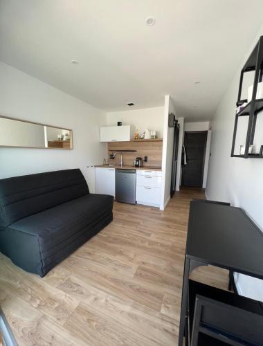 un salon avec un canapé noir et une cuisine dans l'établissement Studio rénové en plein centre ville, sur le port, vue mer, à La Grande Motte