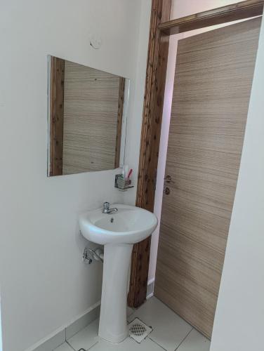 a bathroom with a sink and a mirror and a door at BMW Buxton point Apartment in Mombasa
