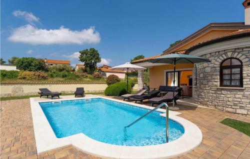 a swimming pool with two chairs and an umbrella at Villa Morena in Buje