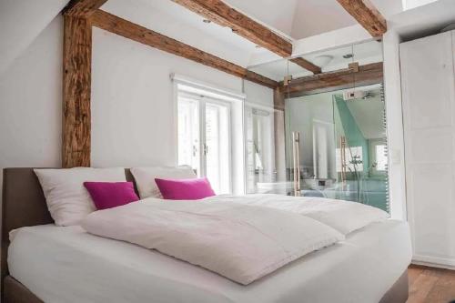 a white bed with pink pillows in a bedroom at Goldene Pastete - Urban Luxury Apartments City Center in Graz