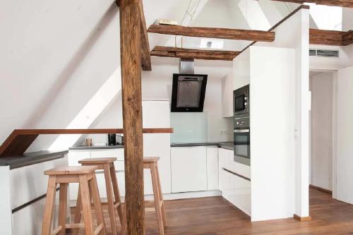 a kitchen with white cabinets and wooden stools at Goldene Pastete - Urban Luxury Apartments City Center in Graz