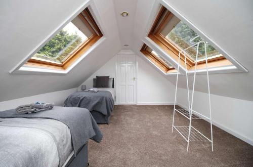a attic bedroom with two beds and two windows at The Lockett Wonderful Large Bungalow Plympton, Plymouth Free Parking By STAE-Homes in Plymouth