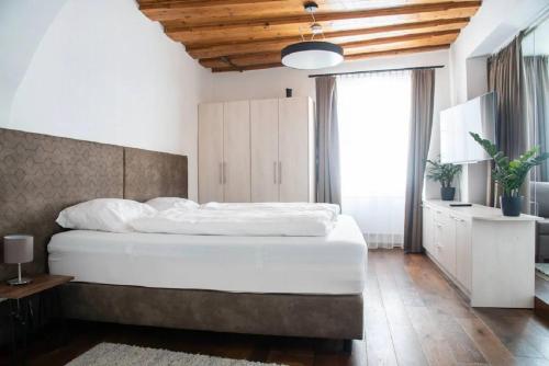a bedroom with a white bed and a large window at Goldene Pastete - Urban Luxury Apartments City Center in Graz
