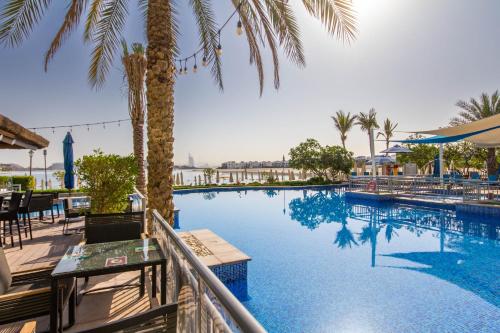 a swimming pool with palm trees and a resort at Bespoke Residences - 2 Bedroom Apartment Sea View with Beach Access in Dubai