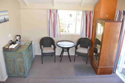 a room with three chairs and a table and a mirror at Le Loft in Akaroa