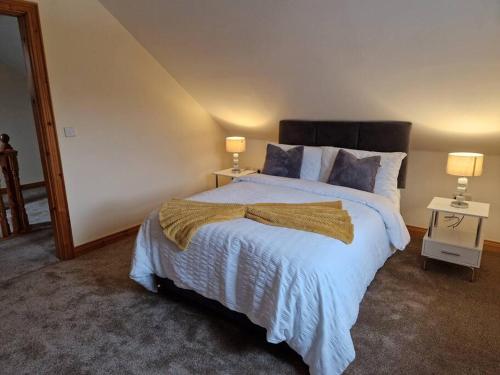a bedroom with a large bed with two lamps at Peartree Cottage in Derryork