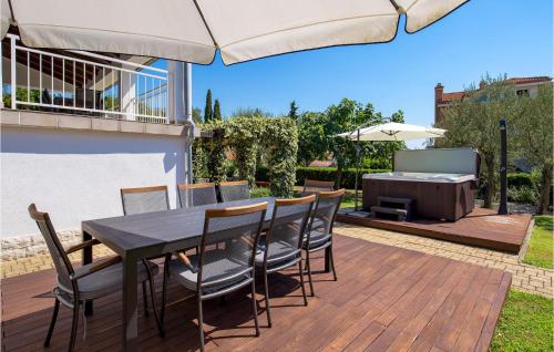 a table and chairs on a wooden deck with an umbrella at 3 Bedroom Cozy Home In Krk in Krk
