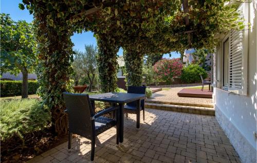 a table and chairs sitting under an ivy covered tree at 3 Bedroom Cozy Home In Krk in Krk