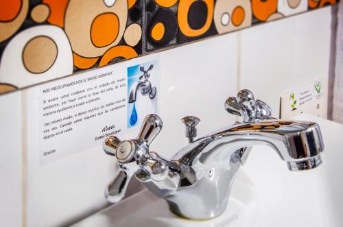 a bathroom sink with a silver faucet and a sign at Alwa Hotel Boutique Standard in Arequipa