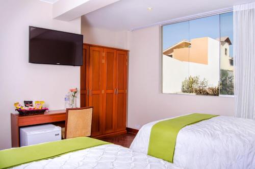 a bedroom with a bed and a desk and a television at Alwa Hotel Boutique Standard in Arequipa
