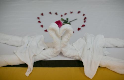 a pair of towels on a bed with a rose at Snow Pearl Homestay Hoi An in Hoi An