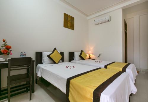 Duas camas num quarto com uma mesa e uma secretária. em Snow Pearl Homestay Hoi An em Hoi An