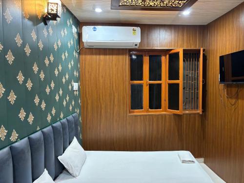 a room with a bed and a window and a television at Bhadra Kali Guest House in Varanasi
