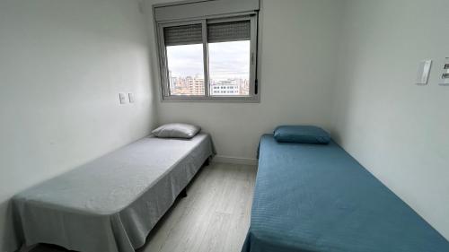 two beds in a room with a window at Dream House - Apto Lindo com Estacionamento Grátis! in Osasco