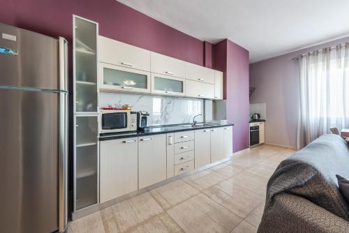 a kitchen with white cabinets and a purple wall at Main square apartment in Durrës