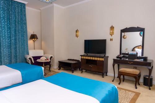 a hotel room with two beds and a desk and a television at Saraya Corniche Hotel in Doha