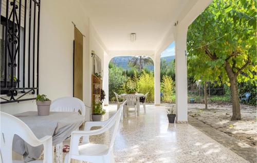 a porch with white chairs and a table and a tree at Lovely Home In Xativa-Almaseretes in Caserío Casa Sanchis