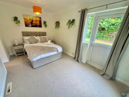 a bedroom with a bed and a large window at 5 Bed House - Pool - Hot Tub - Sauna - Pool Table - Near New Forest and Beach - Sleeps 12 in Ringwood
