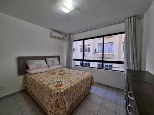 a bedroom with a bed and a large window at Casa a 100 metros da praia de Balneário Camboriú in Balneário Camboriú