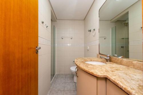 a bathroom with a sink and a toilet and a mirror at Casa a 100 metros da praia de Balneário Camboriú in Balneário Camboriú