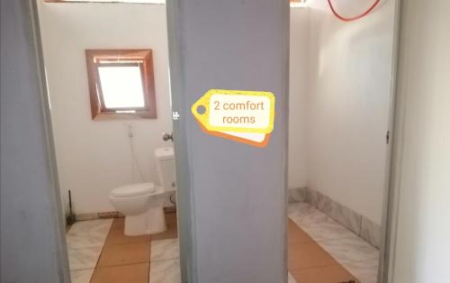 a bathroom with a toilet and a sign on a door at Genevieve Guest House in Maria