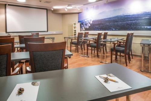a classroom with tables and chairs and a projection screen at Lapland Hotels Oulu in Oulu